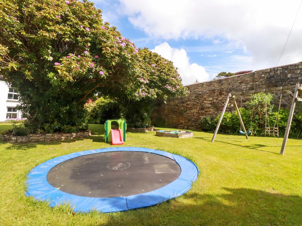 A garden with a trampoline, slide, swing set, and sandbox at Seveock in Threemilestone