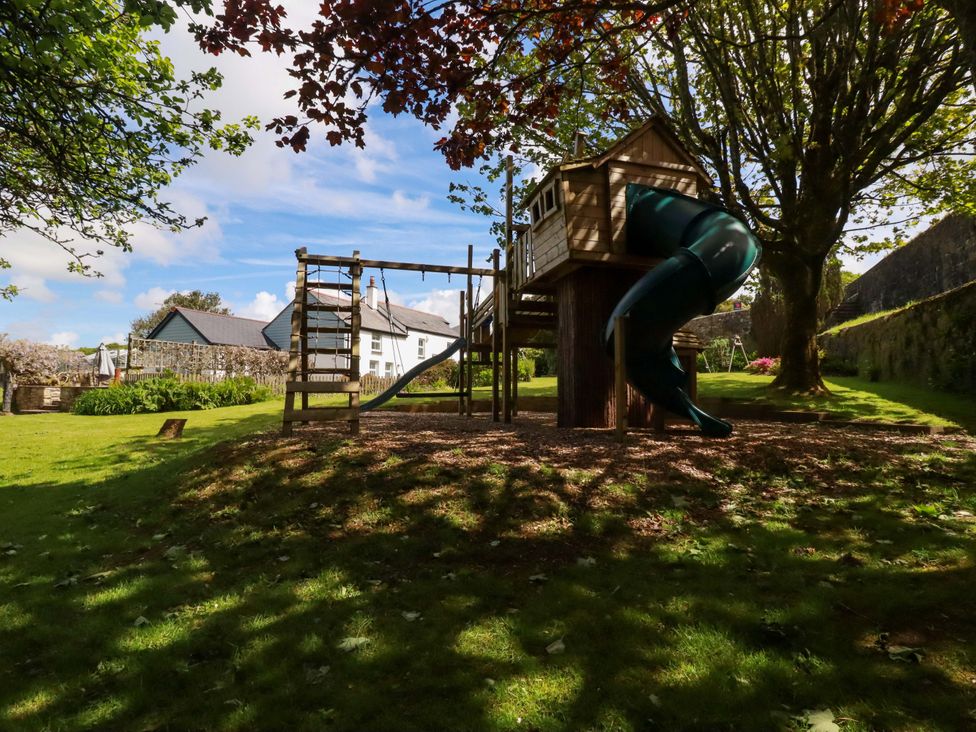 A playhouse with a slide and climbing frame in an outdoor area at Seveock in Threemilestone