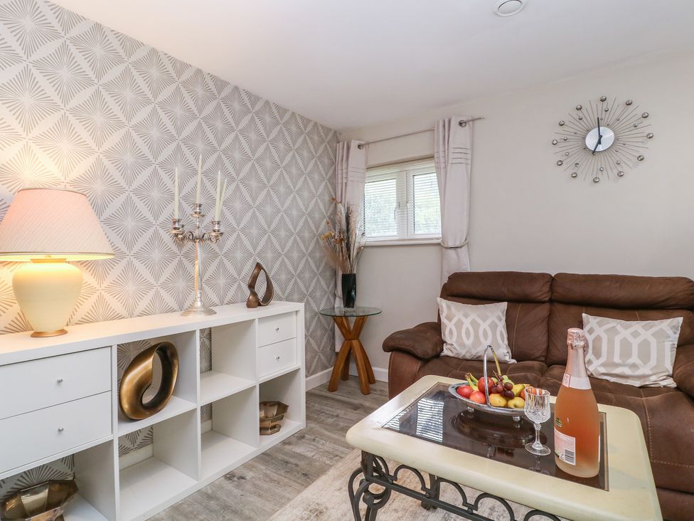 A living room with a sofa and a glass table at Herriots Bridge Cottage Annex in Bristol