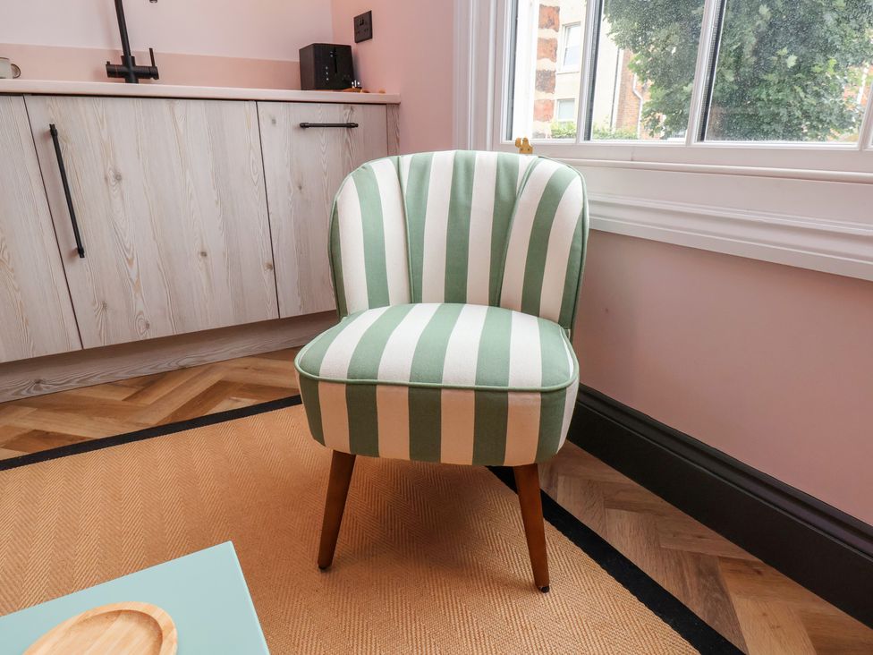 A striped chair near a kitchen unit and window at Apartment Pink