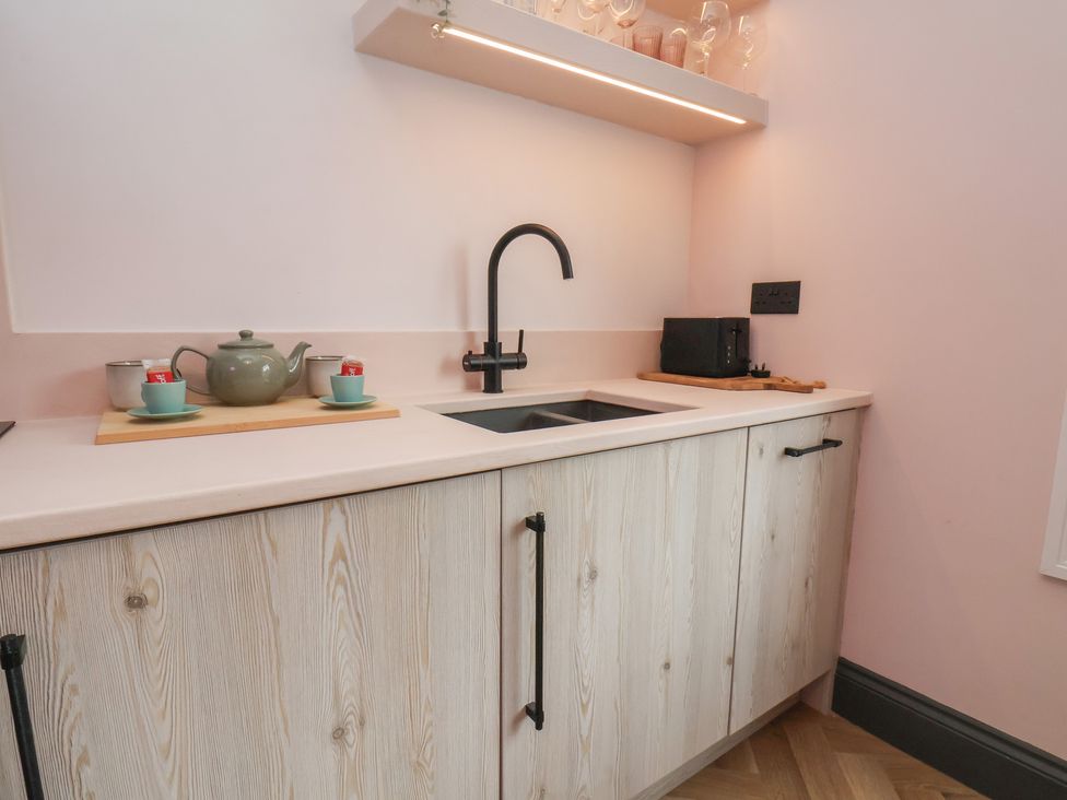 A kitchen with a sink, cabinets, kettle, tea cups, toaster at Apartment Pink