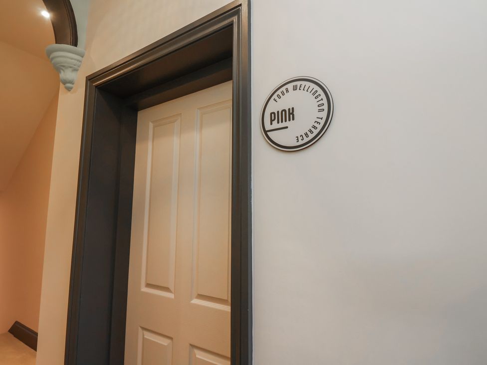 A door with a sign for Apartment Pink at Four Wellington Terrace