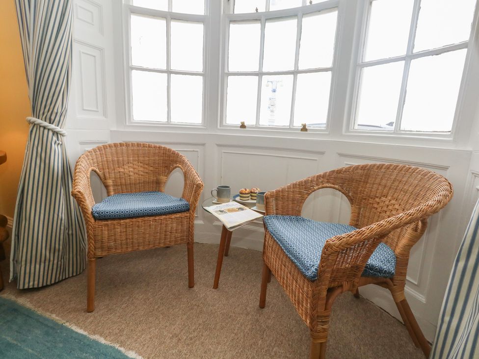 A sitting room with two chairs and a table with mugs and cakes at No 3 By The Sea Weymouth