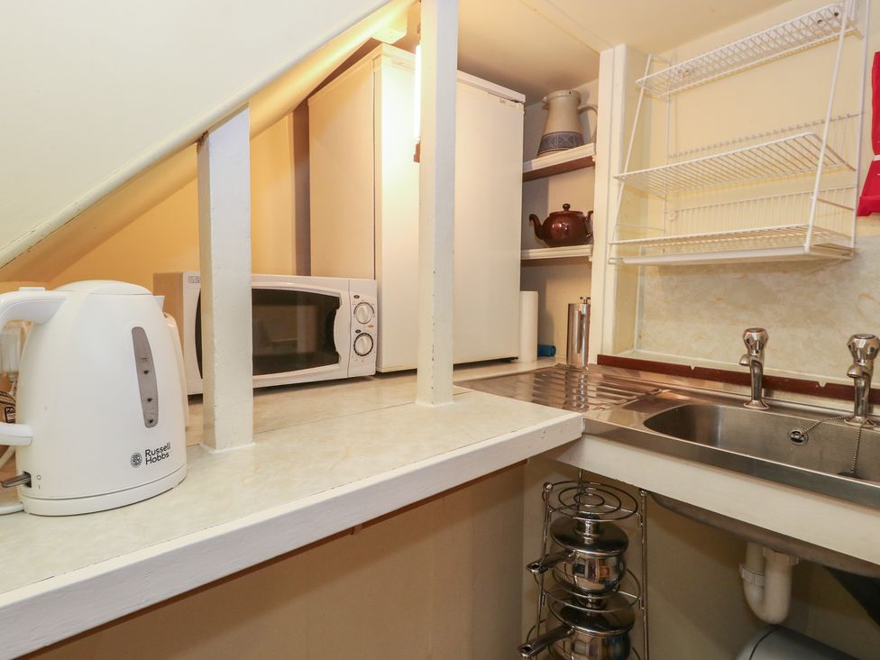 A kitchen with a kettle, microwave, refrigerator, and sink at No 3 By The Sea in Weymouth