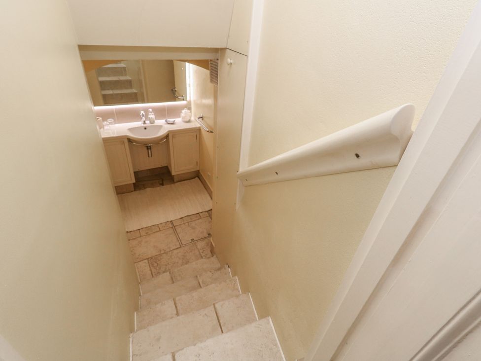 Stairs leading to a bathroom with a sink and mirror at No 3 By The Sea in Weymouth