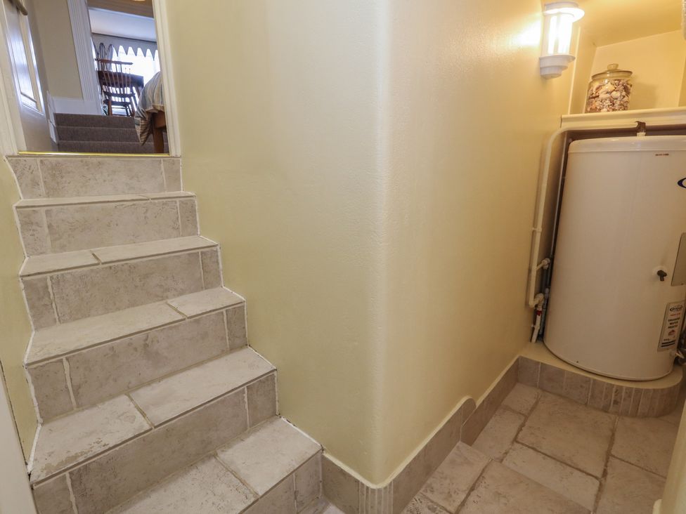 A hallway with stairs leading up and a water heater at No 3 By The Sea in Weymouth