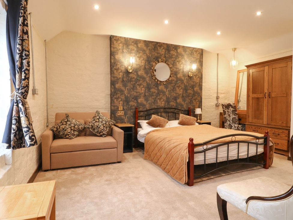 A bedroom with a bed, sofa, wardrobe, and mirror at Stay @ Mantra Stoke Albany