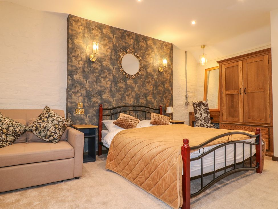 A bedroom with a bed, sofa, and wardrobe at Stay @ Mantra, Stoke Albany