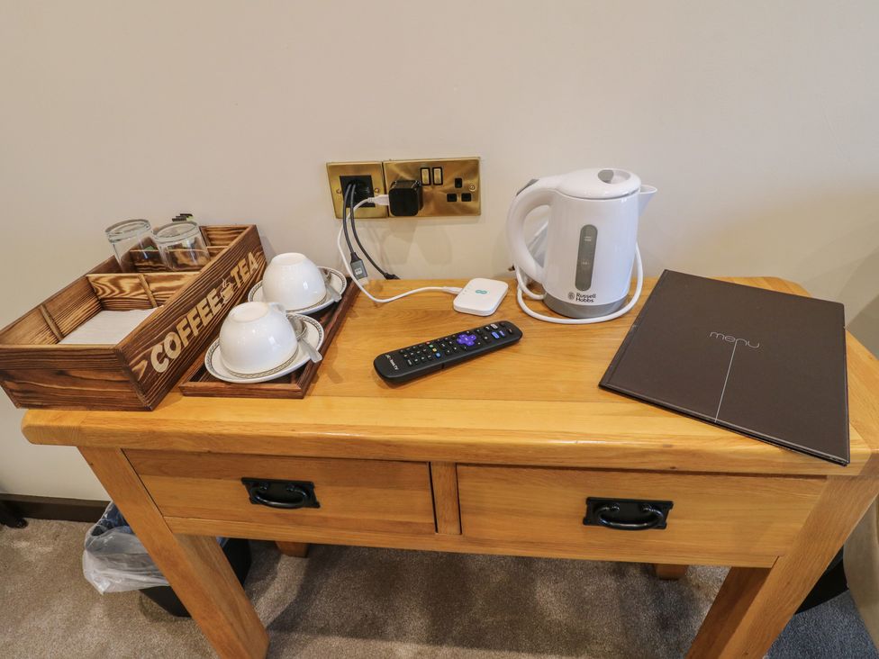 A guest room with a wooden table and kettle at Stay @ Mantra Stoke Albany