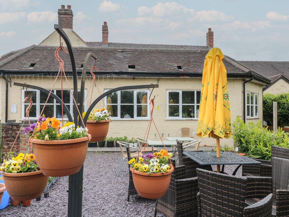 A garden with hanging flower pots and outdoor furniture at Stay @ Mantra Stoke Albany