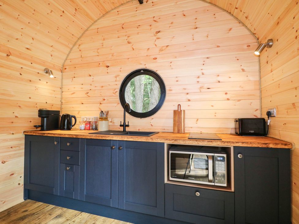 A kitchen with blue cabinets and a round window at Mallard Lodge in Marlow
