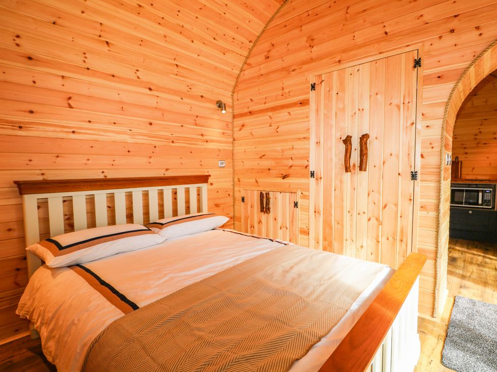 A bedroom with a bed and wooden accents at Mallard Lodge in Marlow
