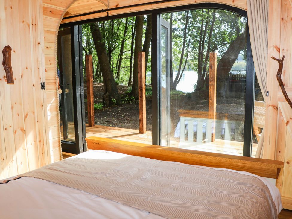 A bedroom with a bed and windows overlooking outdoor scenery at Mallard Lodge in Marlow