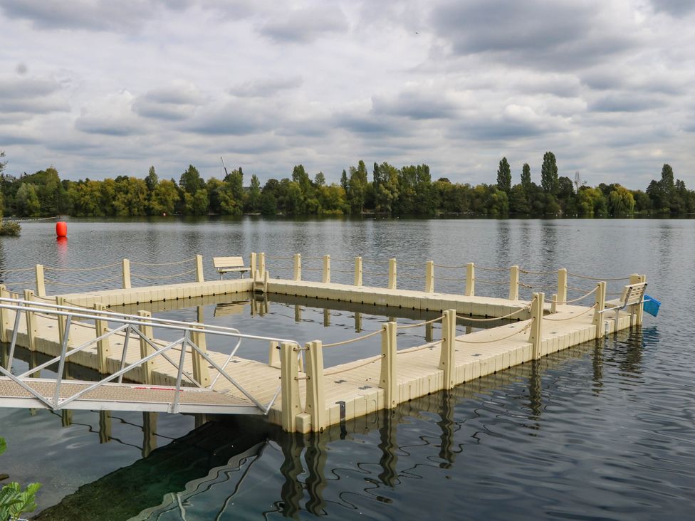 A dock on a lake with trees in the background at Mallard Lodge in Marlow