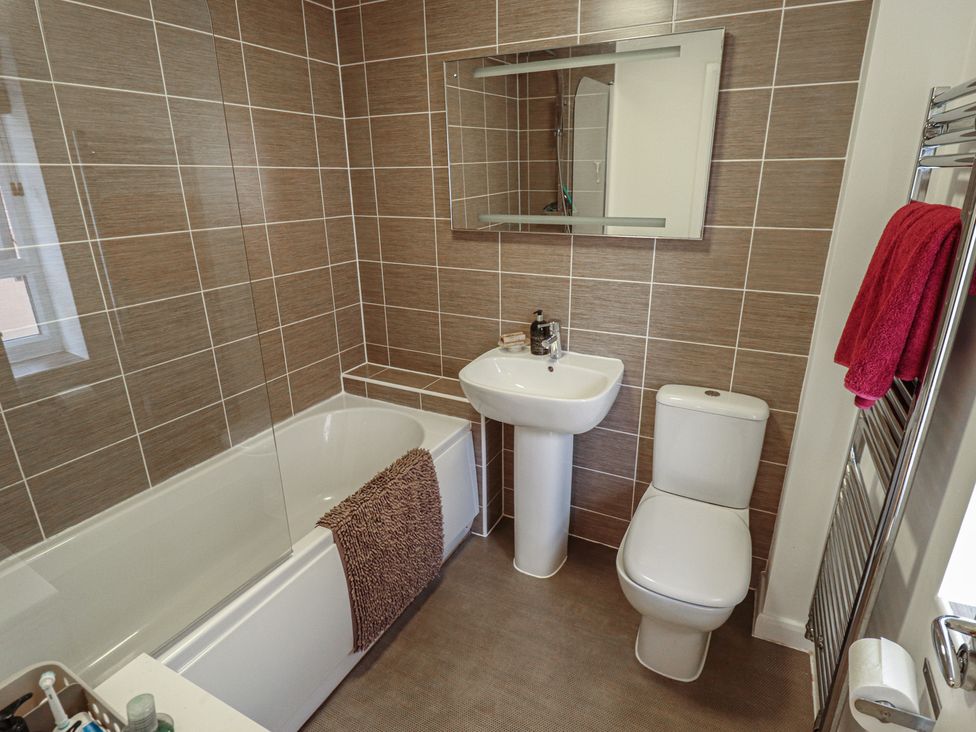 A bathroom with bathtub, toilet, sink, and mirror at 26 Otho Way