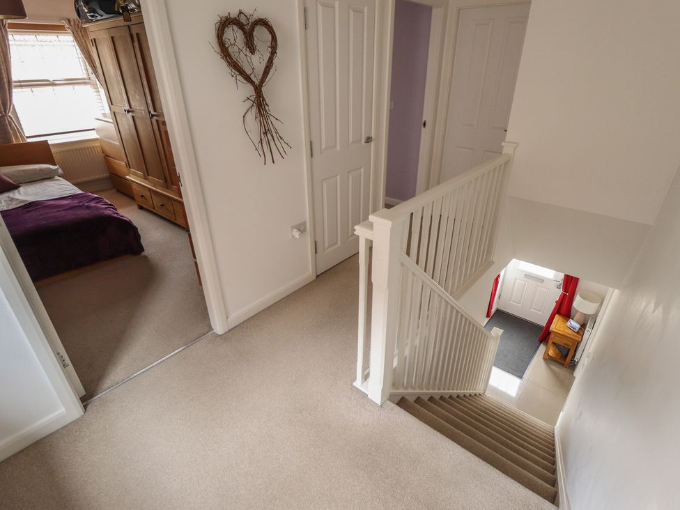 A hallway with a staircase and doors at 26 Otho Way