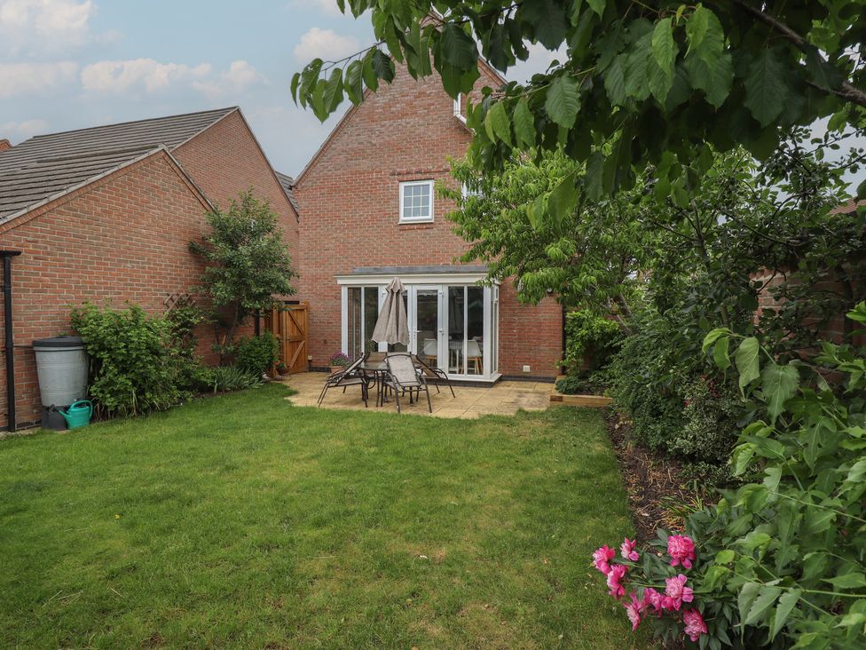 A garden with a table and chairs beside a house at 26 Otho Way