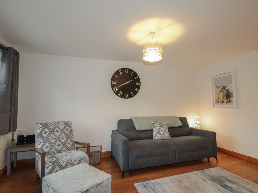 A living room with a clock and a sofa at 39 Knocknagael in Inverness