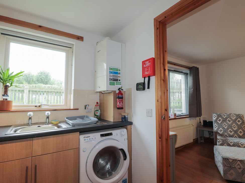 A kitchen featuring a sink, washing machine and window at 39 Knocknagael in Inverness