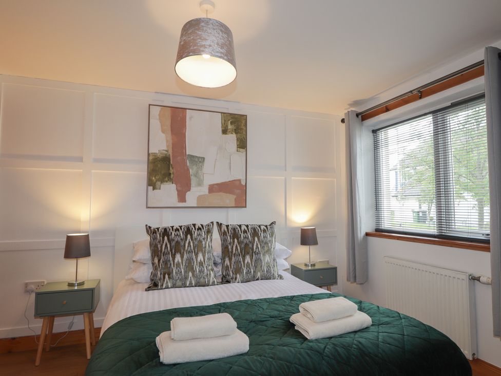 A bedroom with a bed and bedside tables at 39 Knocknagael, Inverness