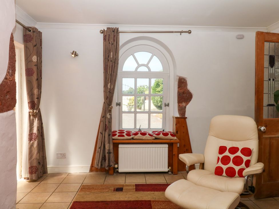 A sitting room with a chair and window at Gorway Cottage in Teignmouth