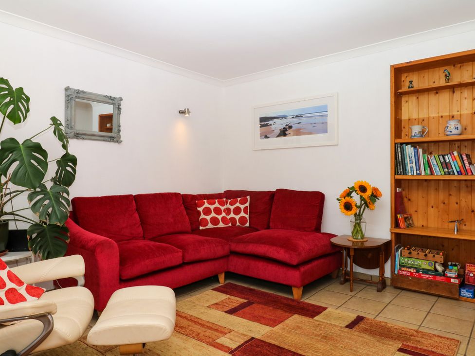 A living room with a red sofa and bookshelf at Gorway Cottage in Teignmouth