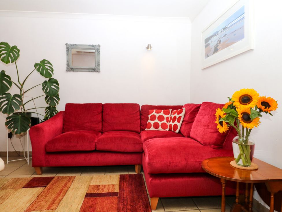 A living room with a red sofa and plant at Gorway Cottage in Teignmouth