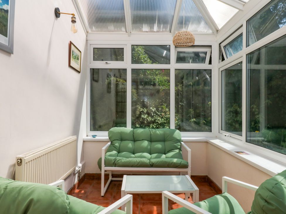 A conservatory with seating and a coffee table at Gorway Cottage in Teignmouth