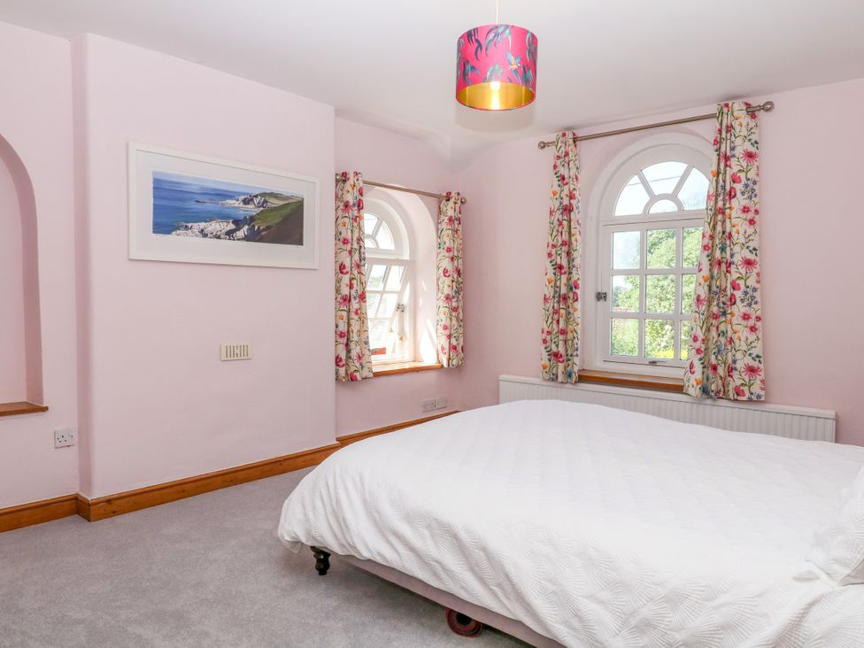 A bedroom with a bed and windows at Gorway Cottage in Teignmouth