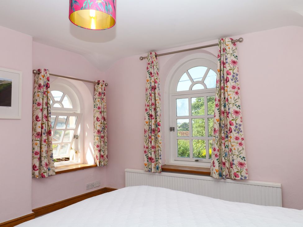 A bedroom with windows and colorful curtains at Gorway Cottage Teignmouth