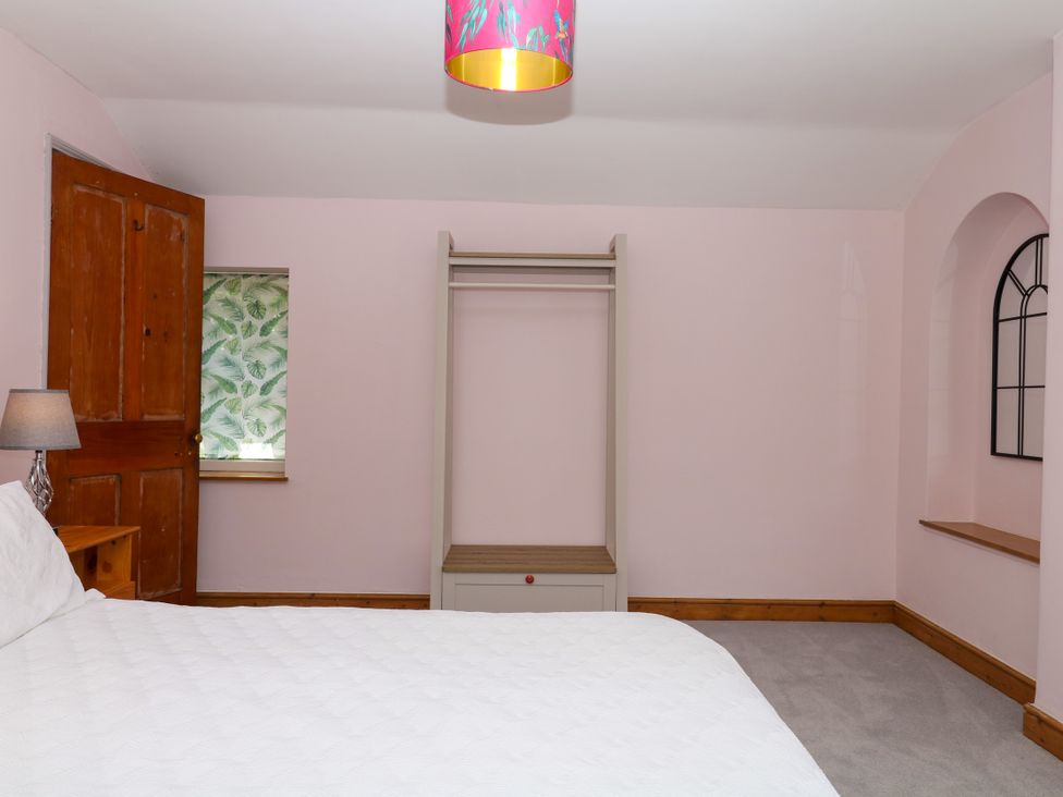 A bedroom with a bed, shelf, and wardrobe at Gorway Cottage Teignmouth