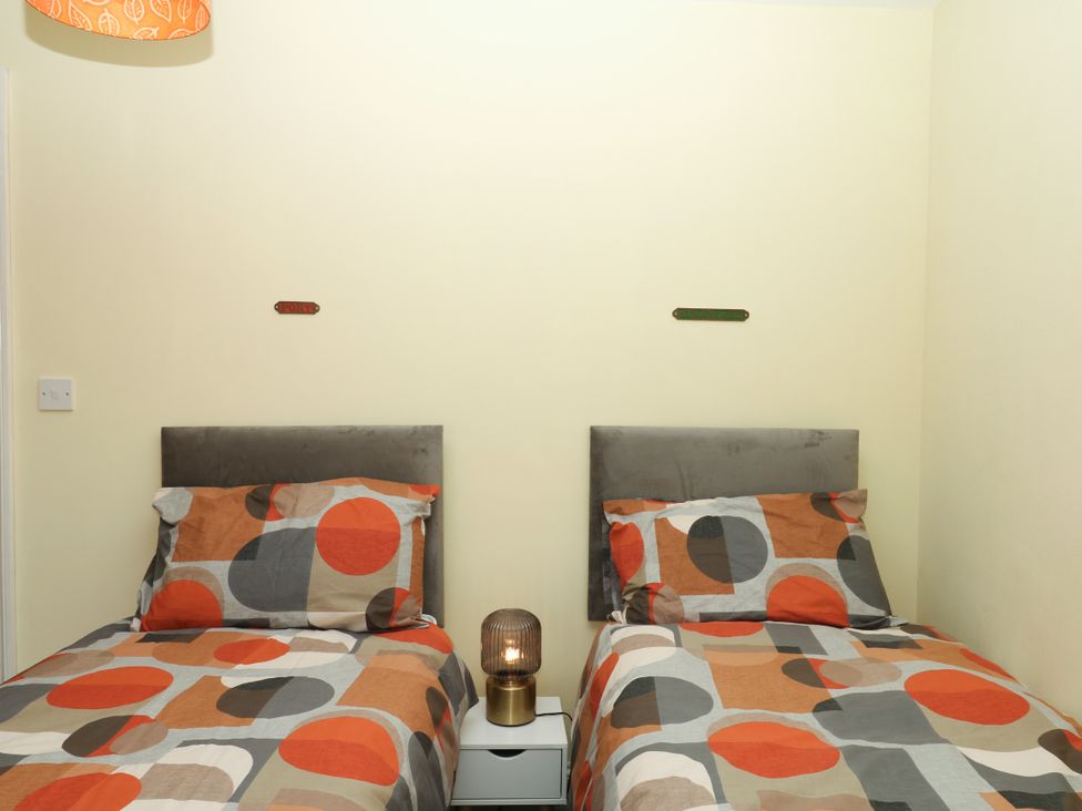 A bedroom with two single beds and a bedside table at Gorway Cottage Teignmouth