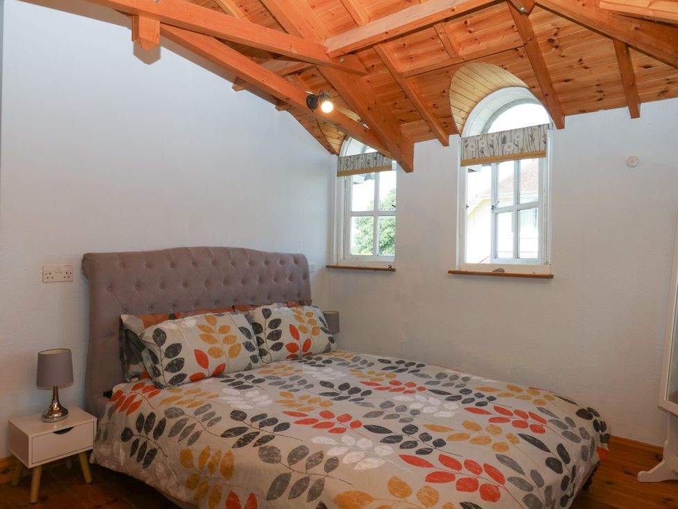 A bedroom with a bed and windows at Gorway Cottage in Teignmouth