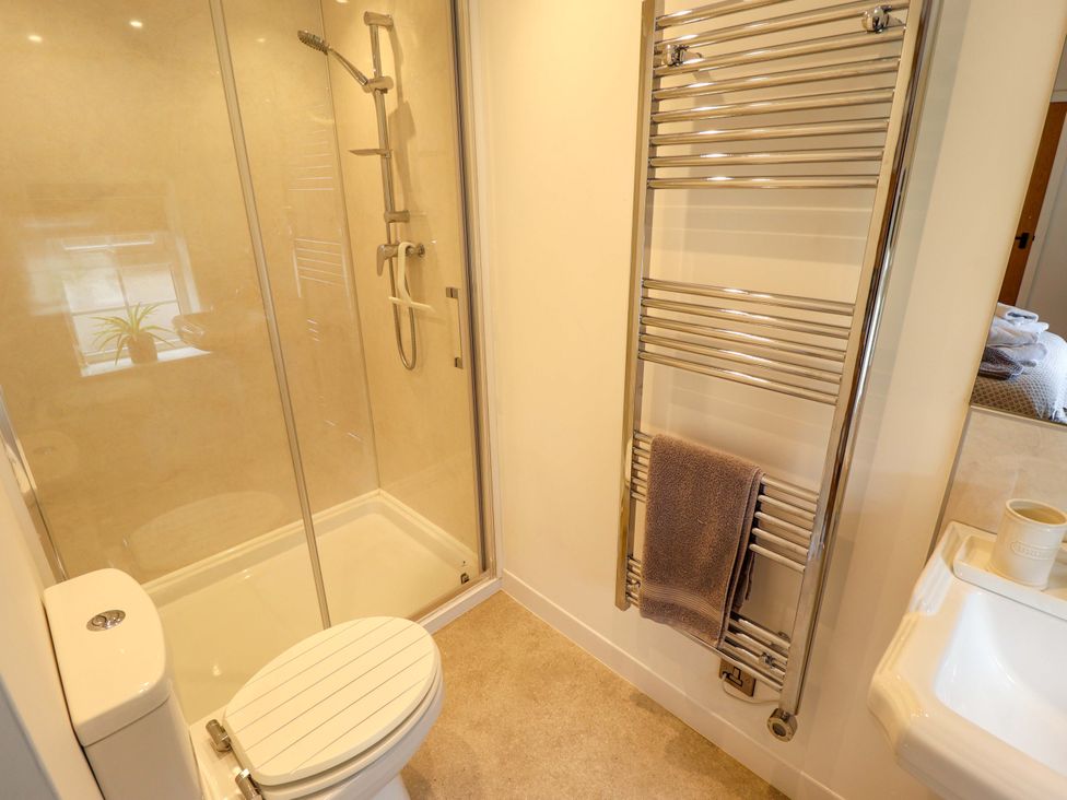 A bathroom with a shower, toilet, towel rack, and sink at The Hen House