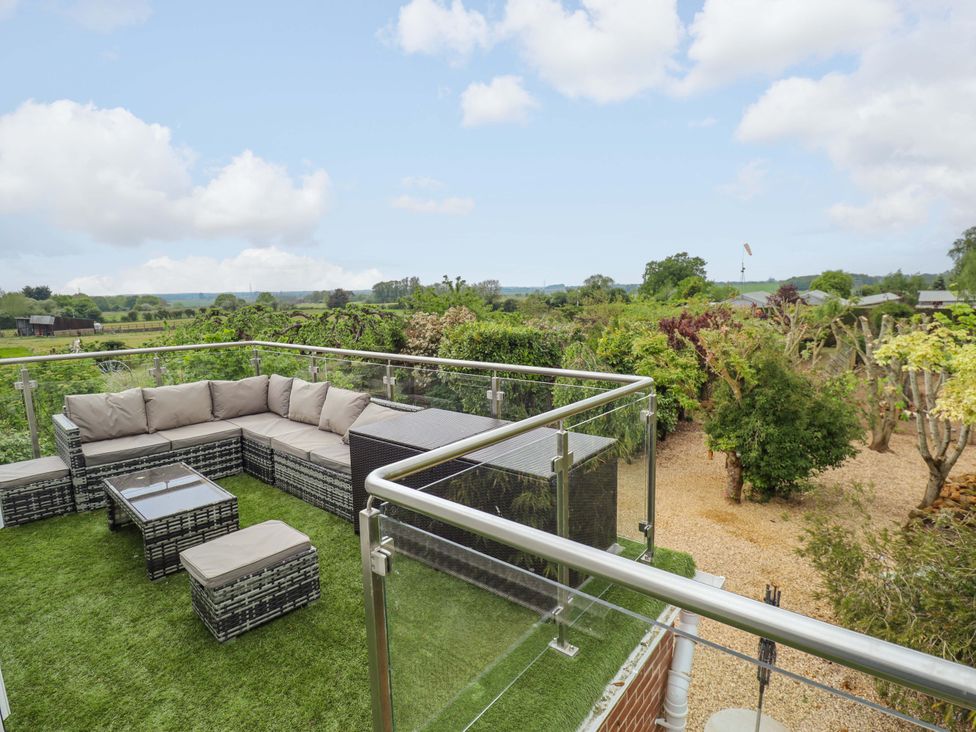 An outdoor seating area with a sofa set and garden view at The Hen House 