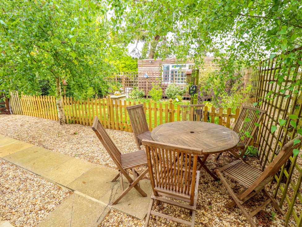 A garden with a wooden table and chairs at The Hen House 