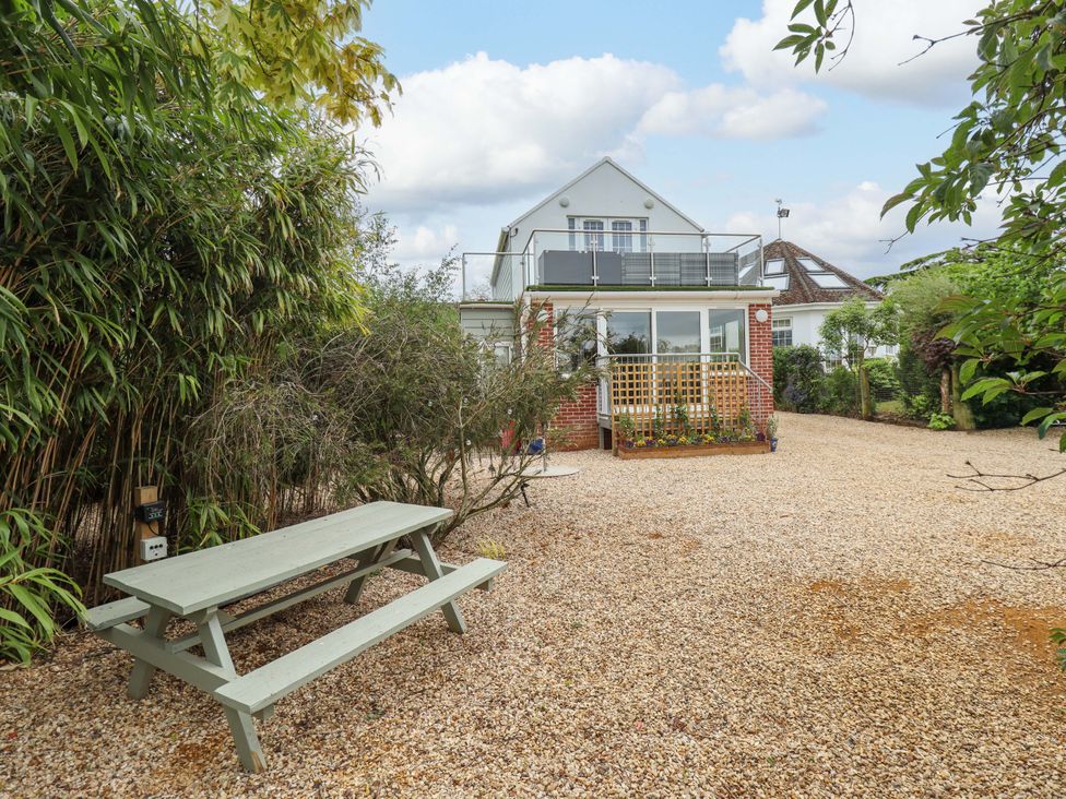 A garden with a house, balcony, and a picnic table at The Hen House 