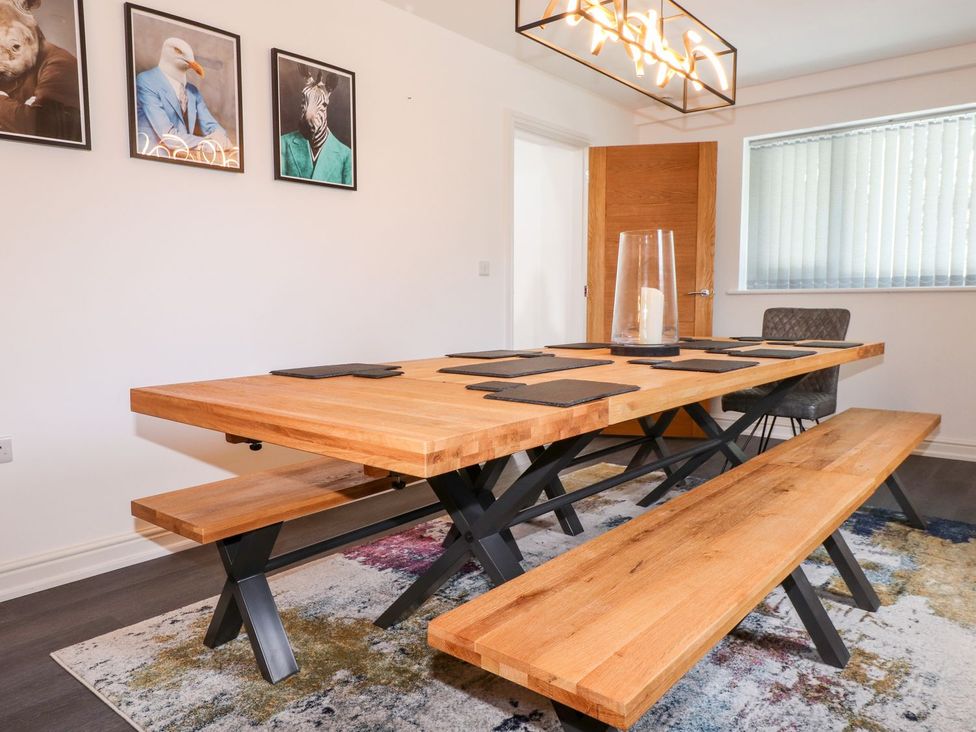 A dining room with a wooden table and benches at Seagull Shack Morfa Bychan