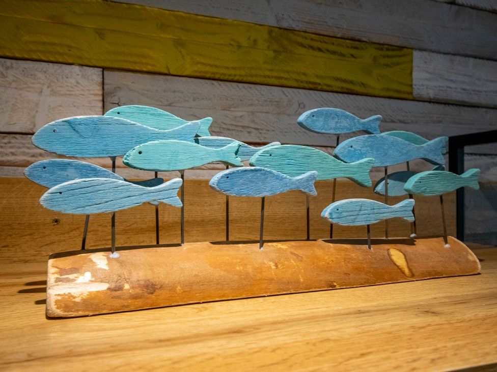 A decorative piece featuring wooden fish on a wooden base at Seagull Shack in Morfa Bychan
