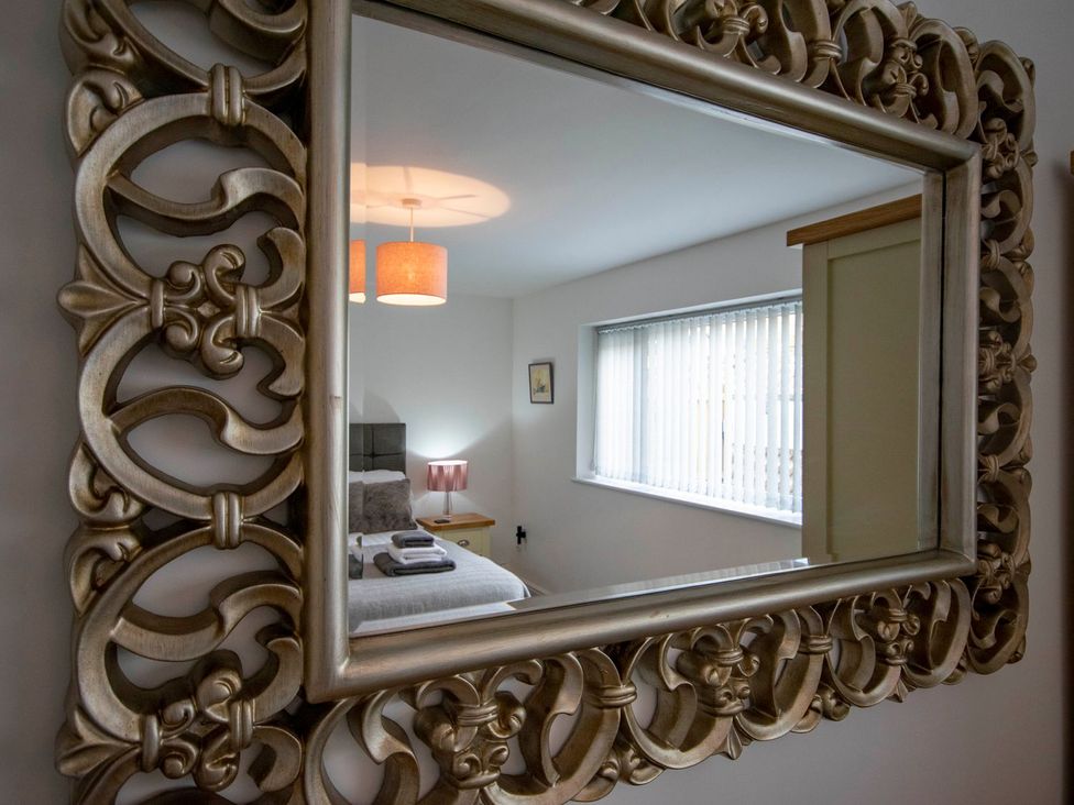 A bedroom with a bed and lamp visible in the mirror at Seagull Shack, Morfa Bychan