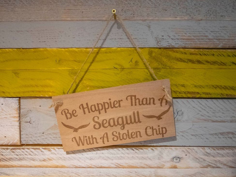 A wooden sign with a saying hanging on a wall at Seagull Shack in Morfa Bychan