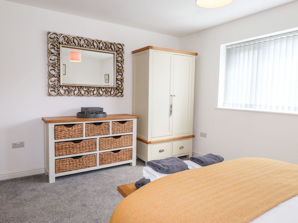 A bedroom with a mirror above a dresser and a wardrobe at Seagull Shack in Morfa Bychan
