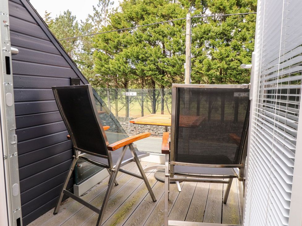 A balcony with chairs and a table at Seagull Shack in Morfa Bychan