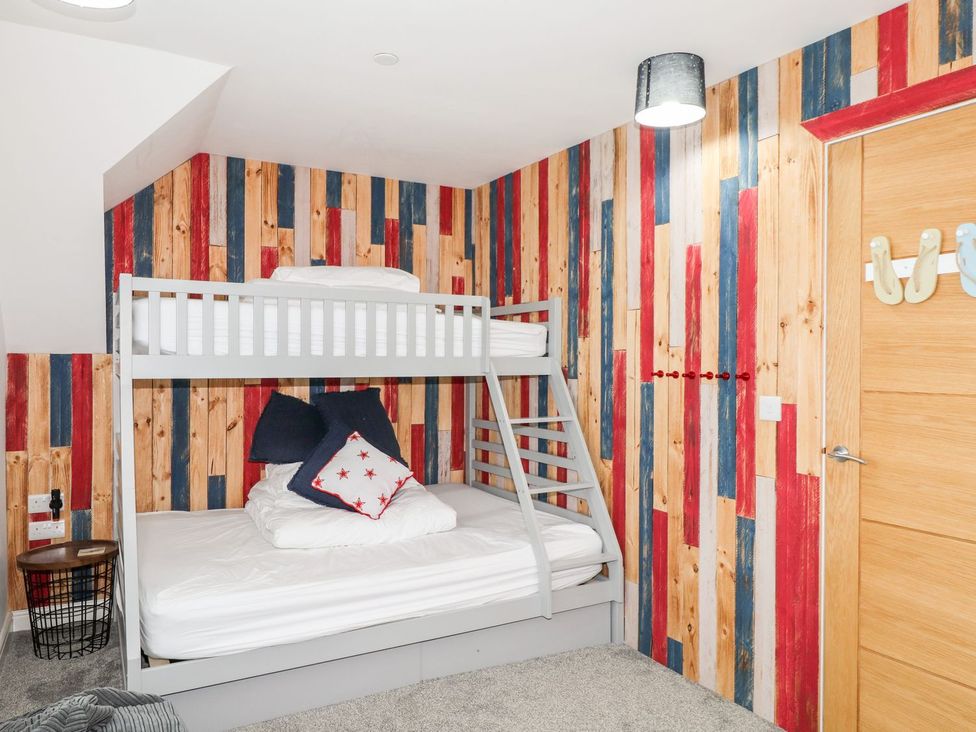 A bedroom with a bunk bed and striped wall at Seagull Shack Morfa Bychan