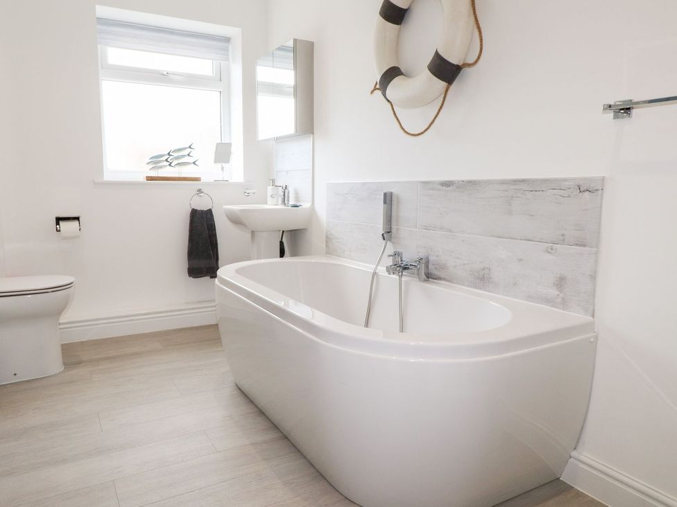A bathroom with a bathtub, toilet, and sink at Seagull Shack in Morfa Bychan