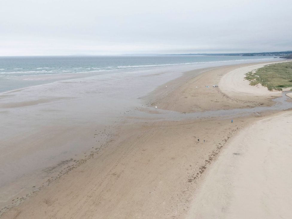 A beach with sand and waves at Seagull Shack Morfa Bychan