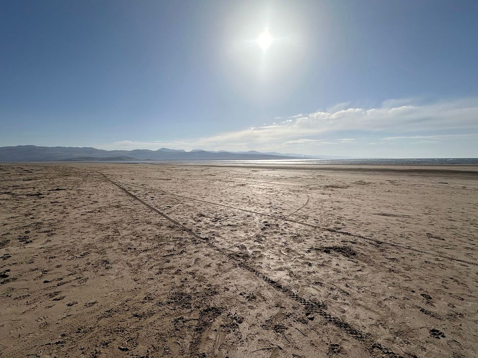 A beach with sand and ocean in the background at Seagull Shack Morfa Bychan
