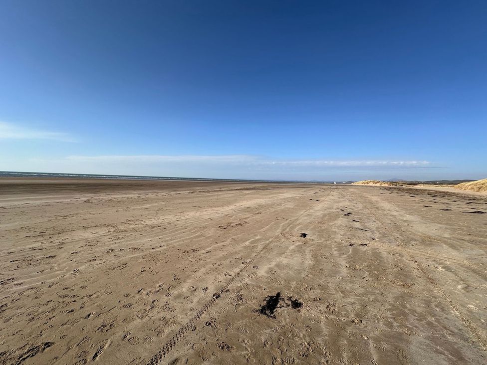 A beach with sand and sea at Seagull Shack Morfa Bychan