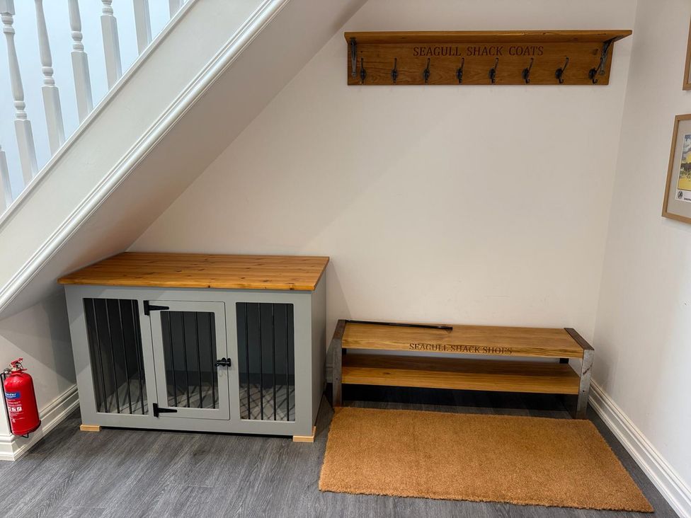A hallway with a coat rack and storage bench at Seagull Shack in Morfa Bychan