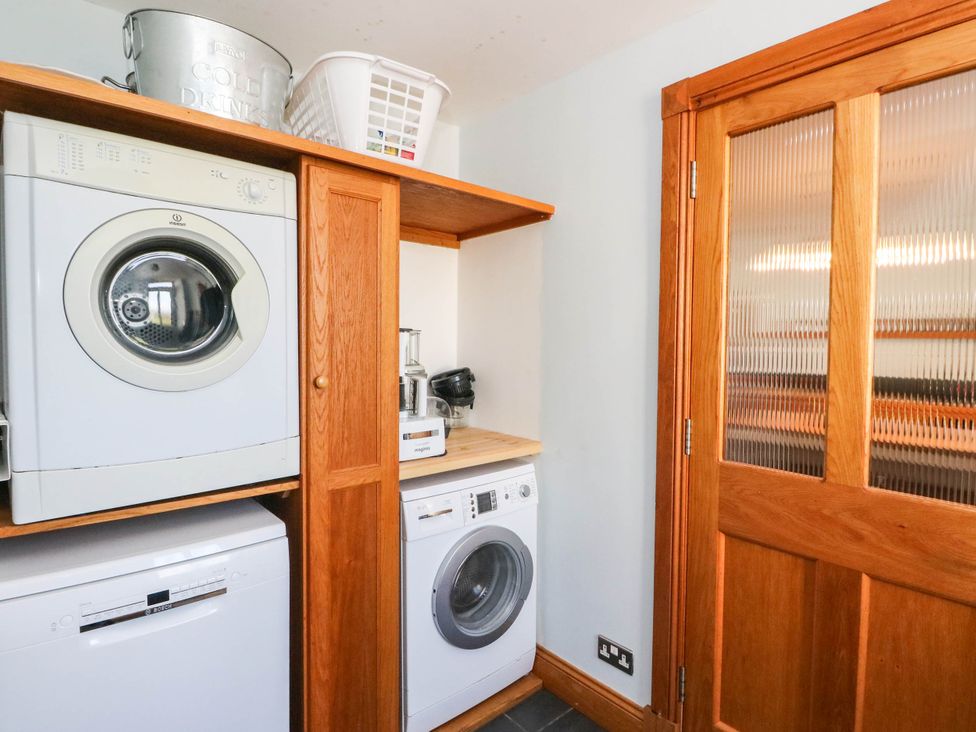 A laundry room with appliances and a basket at Old School House Isle Of South Uist